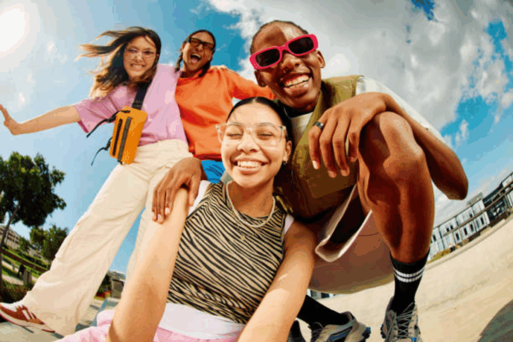 Jovens da Gen z, com roupas coloridas e óculos, fazendo pose para uma self.