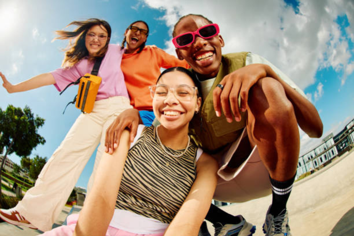 Jovens da Gen z, com roupas coloridas e óculos, fazendo pose para uma self.