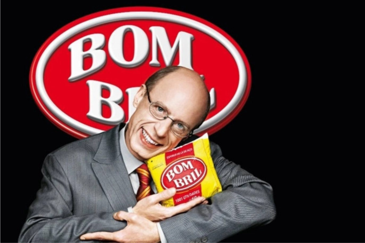 Homem sorridente, de terno, abraçado com um bombril em uma propaganda.